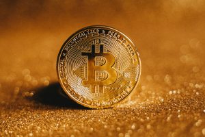 A golden bitcoin on a sandy background