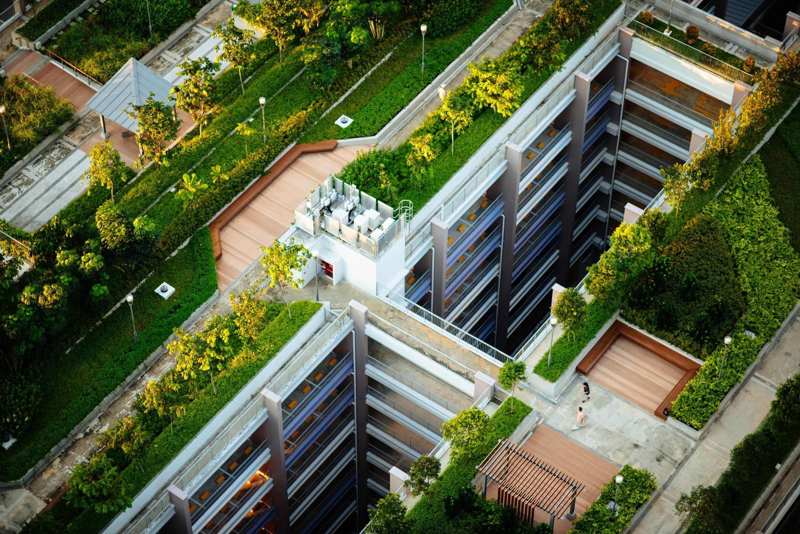 Aerial view of large urban building with walkways and greenery on roof