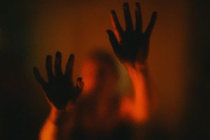 Hands against a foggy glass wall with red cinematic lighting