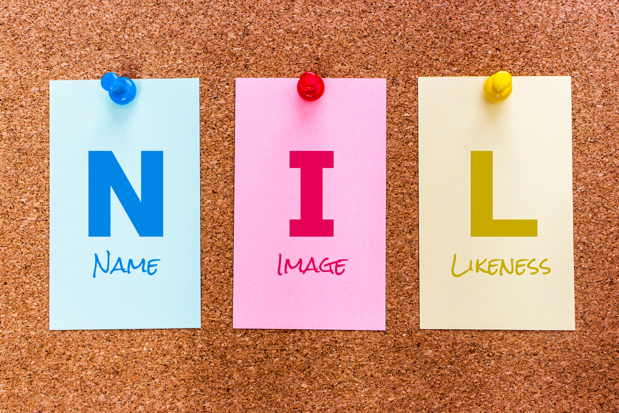 Letters N I L (Name, Image and Likeness) pinned to a corkboard